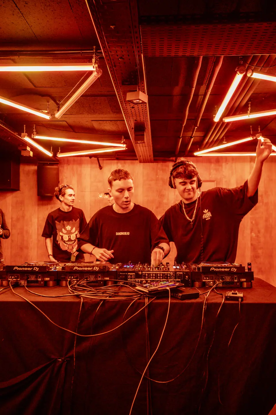 Trois DJ derrière le booth, plafond de néons rouges, Rennes